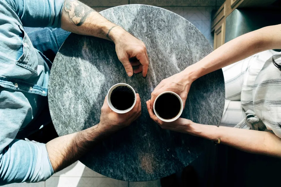 Duas pessoas conversando com café na mesa